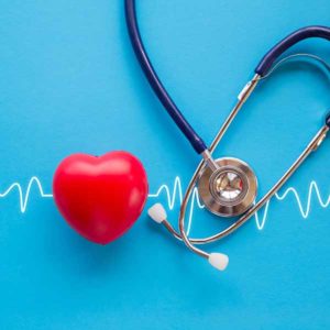 red rubber heart and stethoscope on blue background with cardiogram, health concept