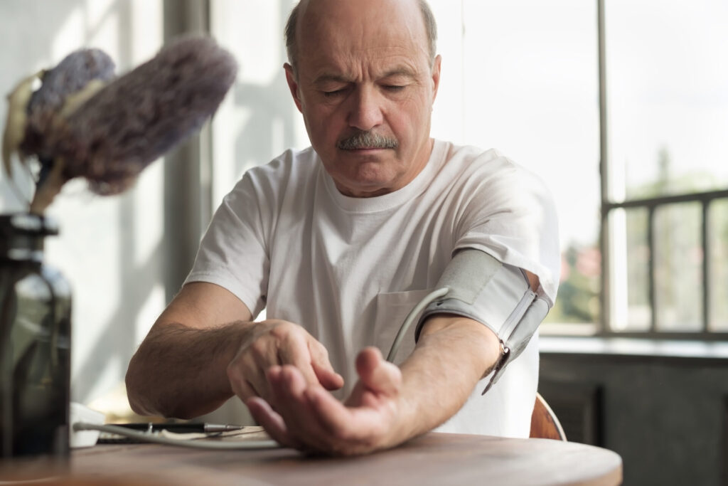 Man uses home blood pressure machine in his kitchen to check his vital statistics.